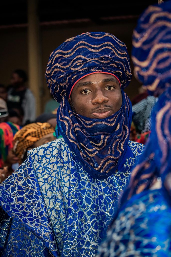 Portrait of a man wearing traditional Hausa attire during a vibrant cultural festival, highlighting rich regional fashion.